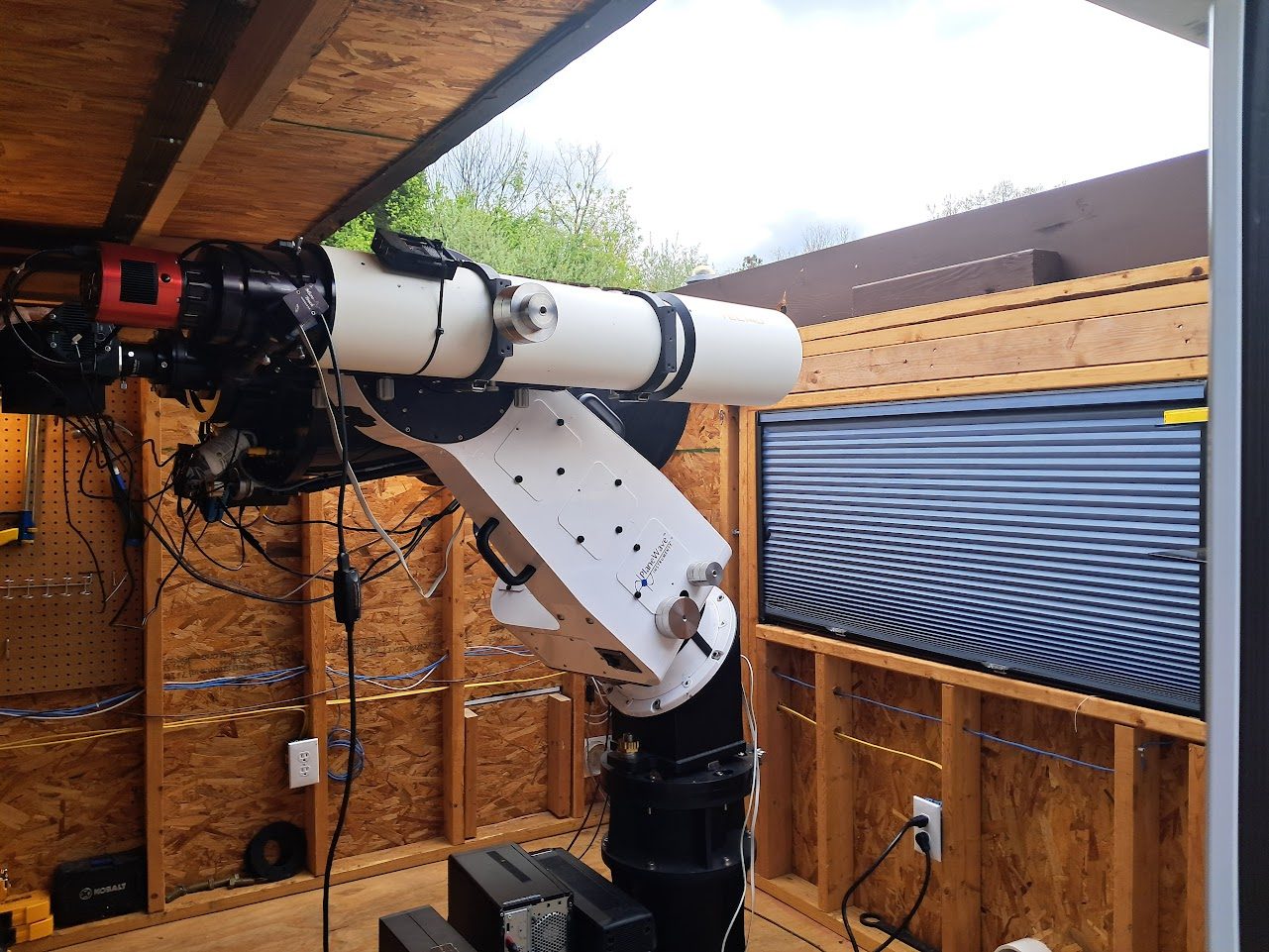 Telescope and red astronomy camera inside roll-off roof observatory